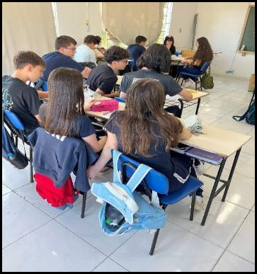 Grupo de pessoas sentadas em sala de aula

Descrição gerada automaticamente
