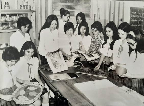 Foto preta e branca de grupo de pessoas sentadas ao redor de uma mesa

Descrição gerada automaticamente
